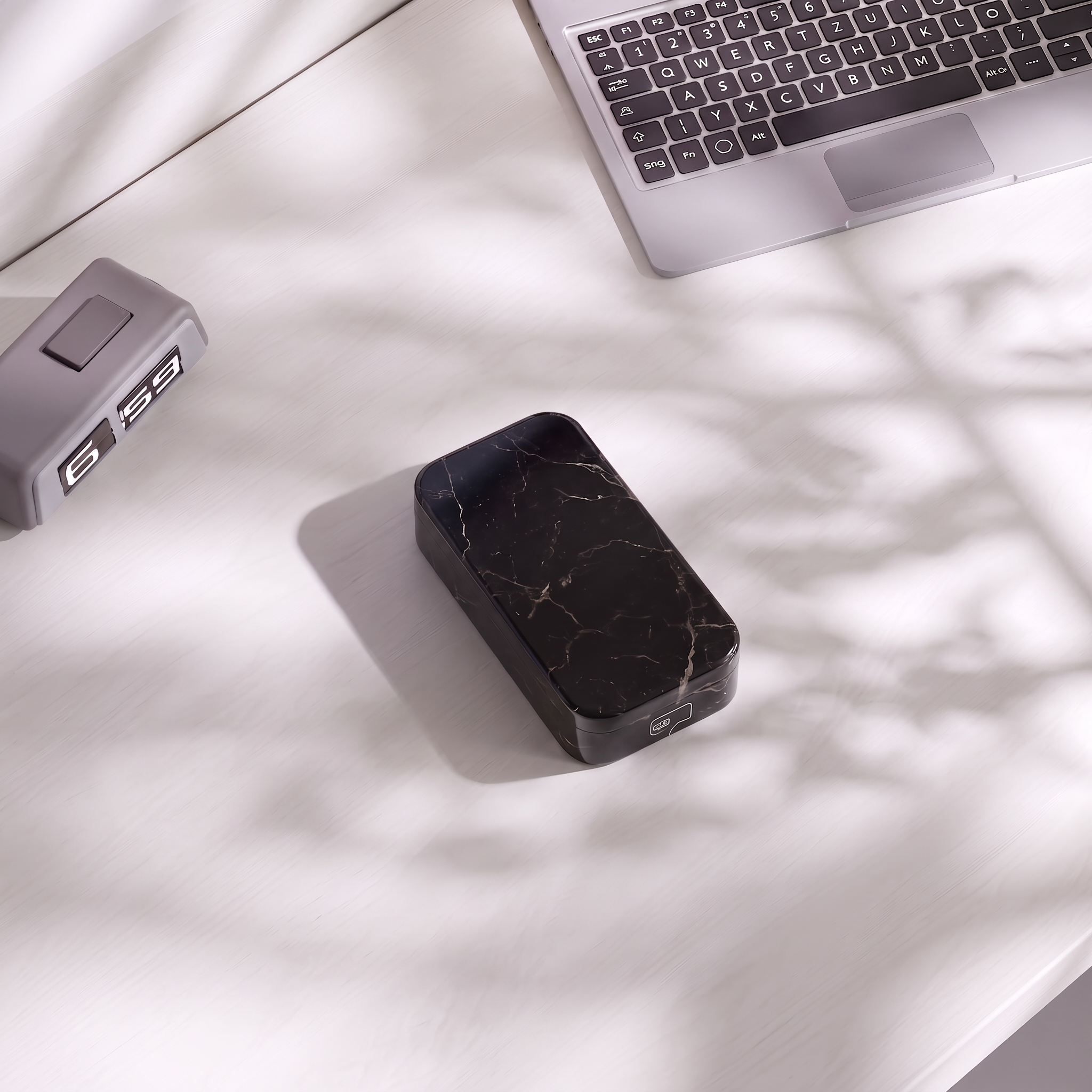 Phone Casket in black marble sealed on a white desk in dappled light